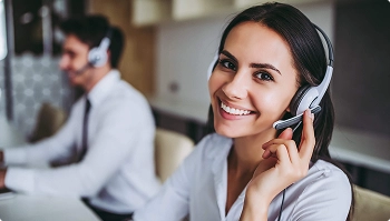 Smiling customer support agent wearing a headset at a desk