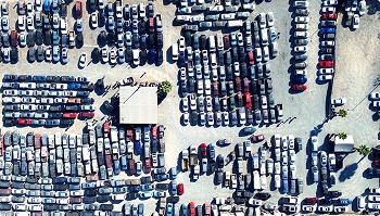 Top down aerial of a crowded auto auction lot with rows of parked vehicles