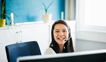 smiling customer service representative wearing headset at desk