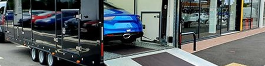 blue car being loaded into enclosed auto transport trailer