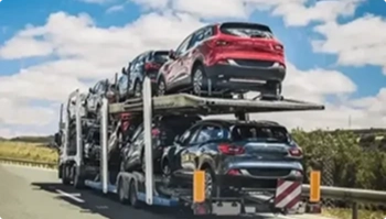 multiple vehicles on a red auto transport trailer on the highway