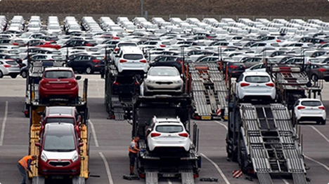 multiple car carriers loading vehicles at a large dealership lot showing reseller auto transport