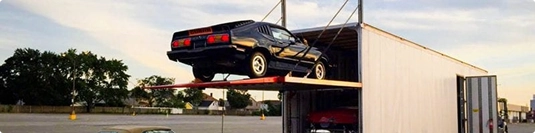 black classic car loading into enclosed trailer with hydraulic lift for secure transport