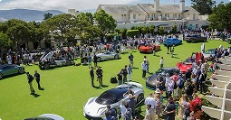 crowd viewing collector vehicles on green lawn at outdoor concours style car show