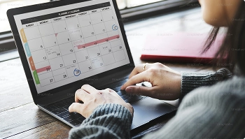person checking a calendar on a laptop to schedule car shipping pickup dates