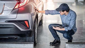 technician inspecting a vehicle and recording condition during delivery