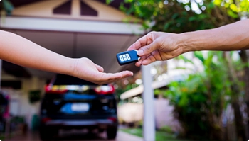 person handing over car keys during door to door vehicle delivery service