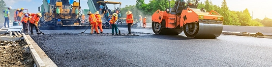 road construction workers paving fresh asphalt to improve vehicle transport routes