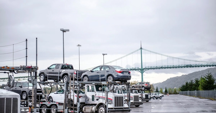 car transport trucks parked near a bridge on a cloudy day