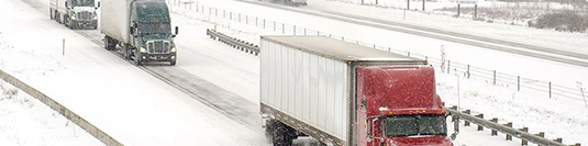 trucks driving on a snowy road illustrating weather delays
