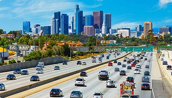 busy los angeles freeway with downtown skyline on a clear sunny day
