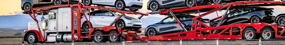 red open car hauler transporting electric vehicles across highway