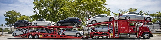 red open car hauler loaded with multiple vehicles parked roadside