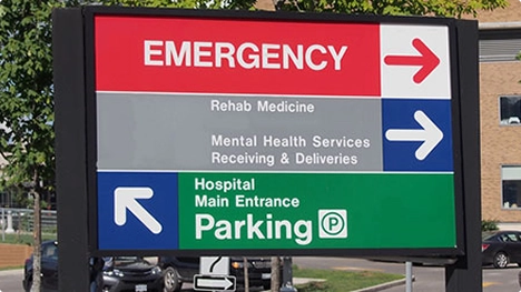 Hospital sign showing directions to Emergency, Rehab Medicine, Mental Health Services, and parking