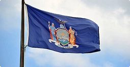 New York state flag waving against a blue sky