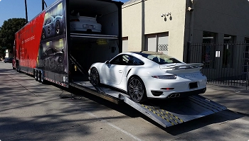white sports car loading into enclosed trailer via ramp for secure luxury transport