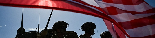 american flag waving with silhouetted soldiers and vehicles symbolizing pcs auto transport