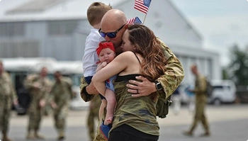 service member hugging family on tarmac with us flag after deployment symbolizing trusted transport