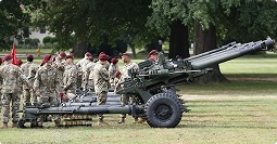 service members standing with field artillery during training on base
