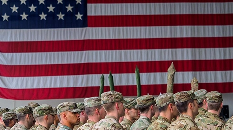 service members standing in formation in front of a large american flag symbolizing military car shipping support