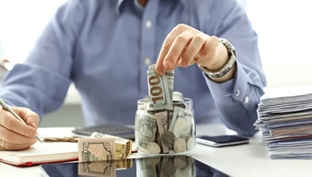 stacking dollar bills beside paperwork symbolizing savings on delivery