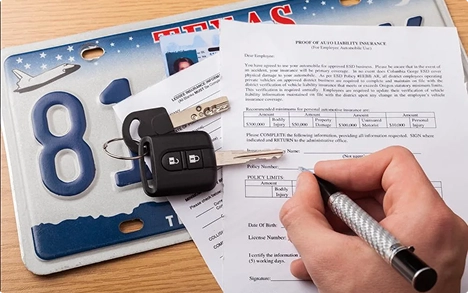 person signing car insurance papers beside Texas license plate and keys