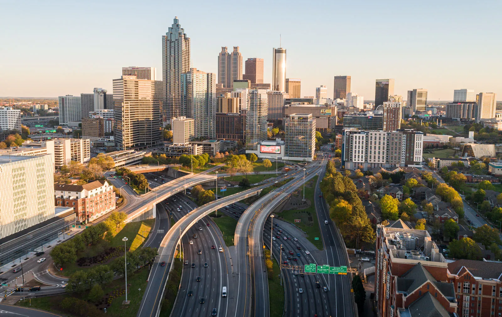 Aerial view of the Atlanta skyline with intersecting highways, downtown skyscrapers, and surrounding neighborhoods in daylight