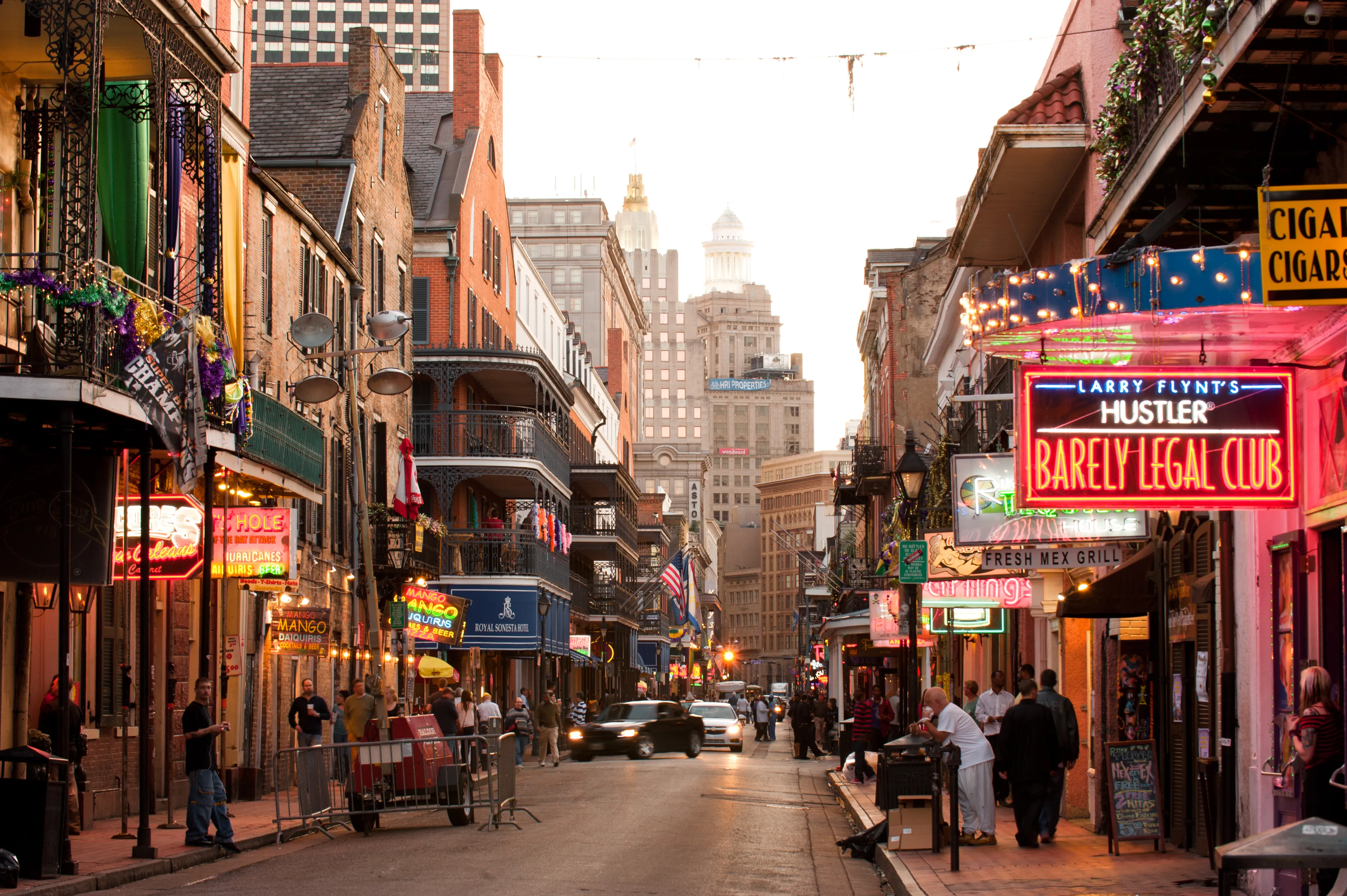 Evening view of Bourbon Street with neon signs, historic buildings, and pedestrians in the French Quarter