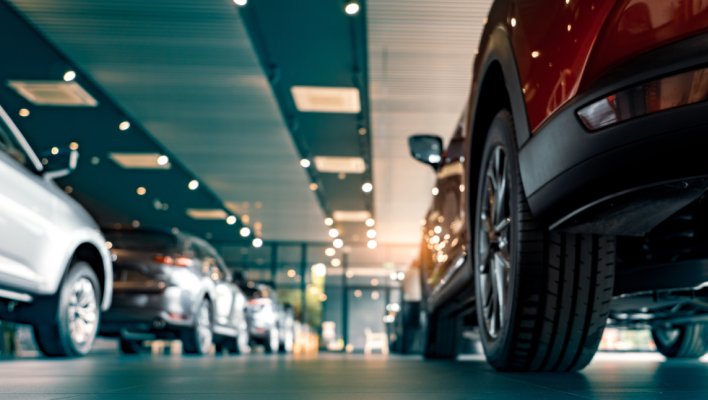 Low angle view of multiple vehicles lined up inside a modern car dealership showroom with indoor lighting
