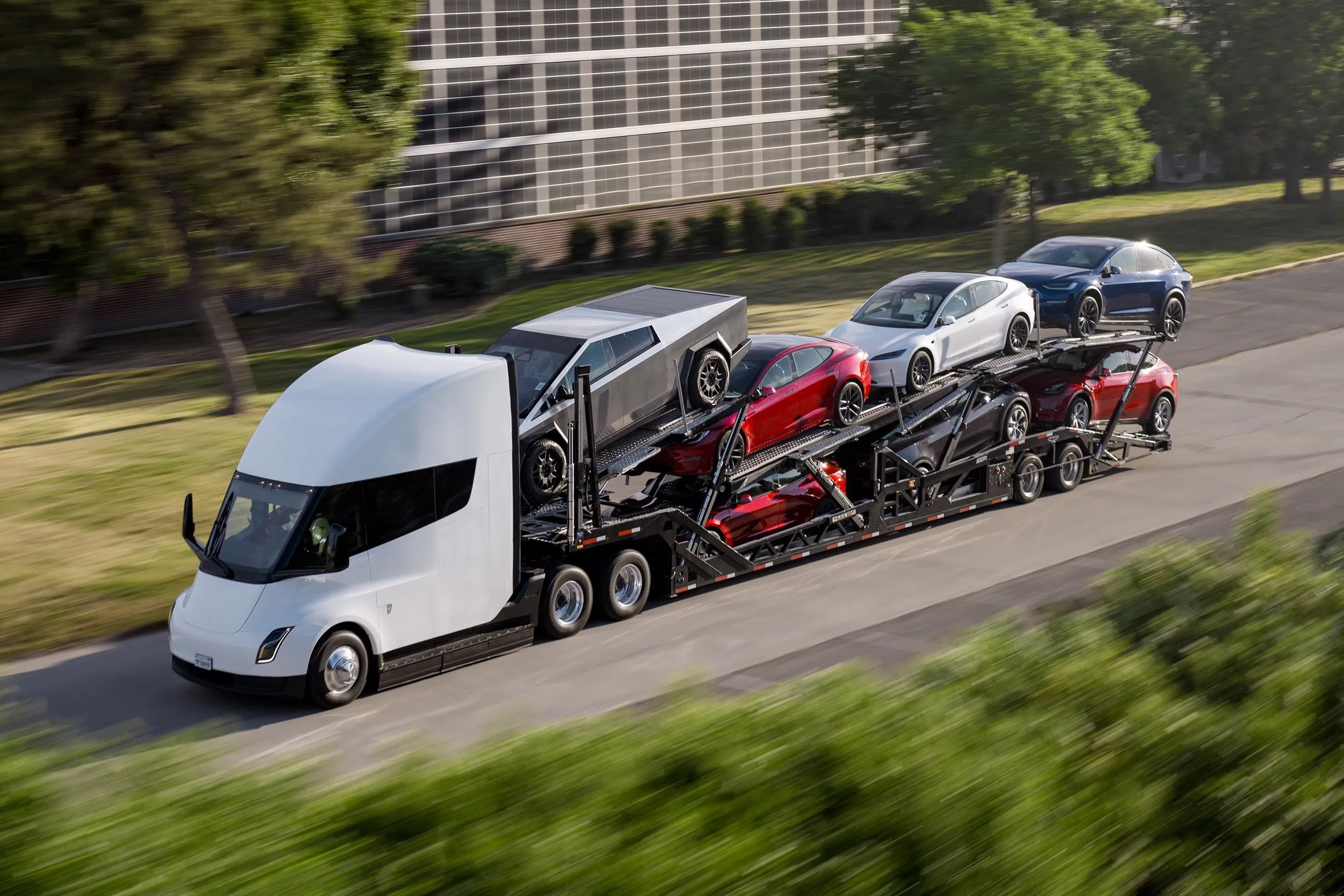 Electric semi truck transporting multiple vehicles on a multi level car carrier along a roadway
