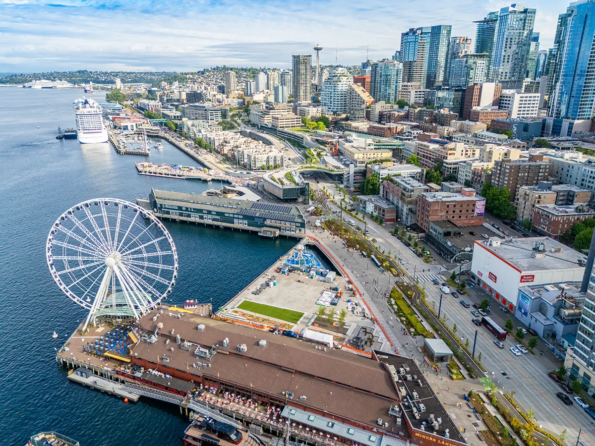 Aerial view of the Seattle waterfront featuring the Seattle Great Wheel, downtown buildings, and Elliott Bay