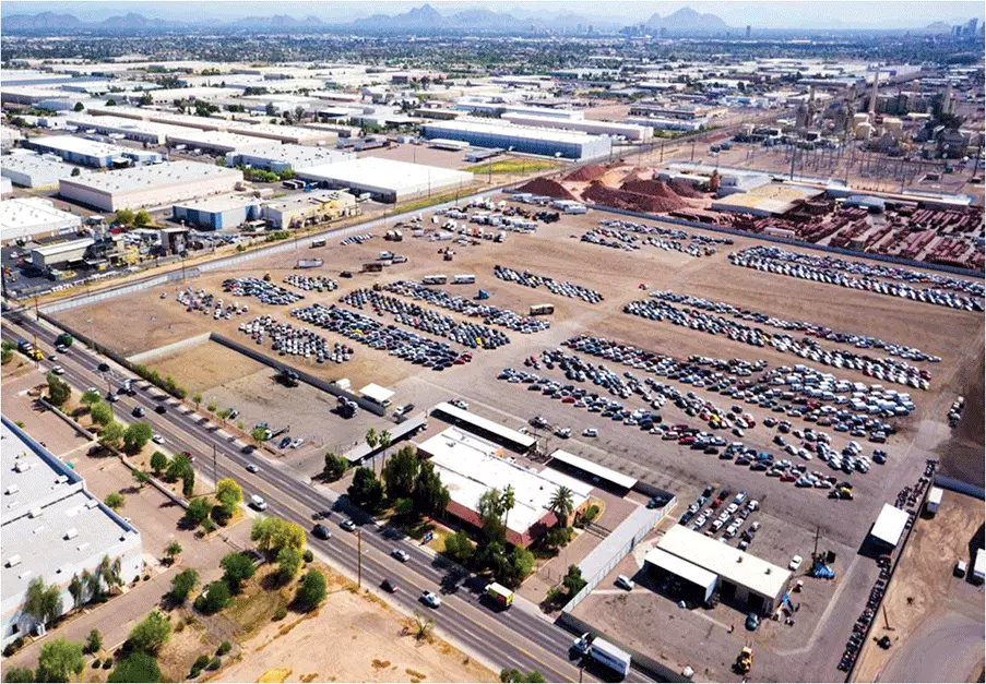 Aerial view of a large auto auction yard in the Phoenix area with rows of vehicles, surrounding roads, and industrial buildings in daylight