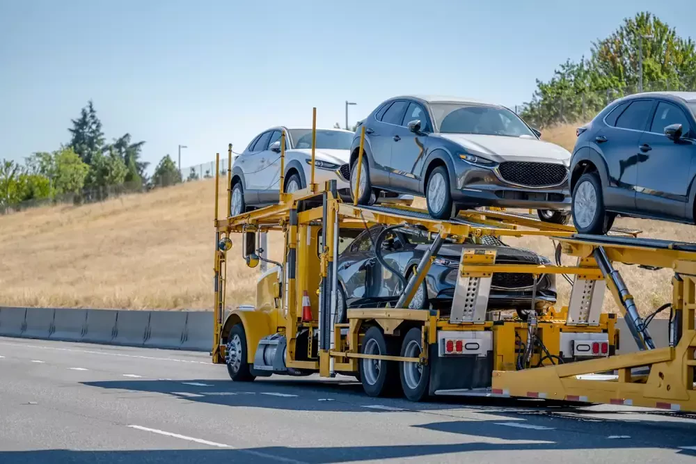 open car transport trailer hauling multiple vehicles on a highway during auto shipping