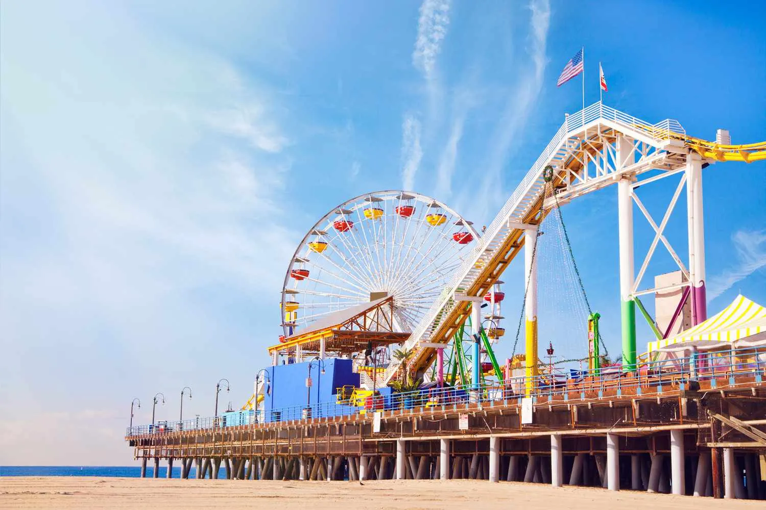 Santa Monica Pier with Ferris wheel and amusement rides along the oceanfront under a clear blue sky