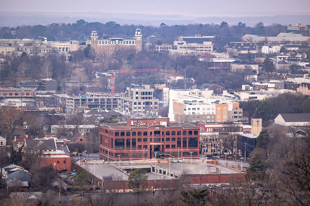 View of an Arkansas city skyline with downtown buildings, residential neighborhoods, and surrounding hills
