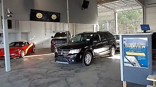 Vehicle being inspected inside an indoor car auction facility with multiple cars on display