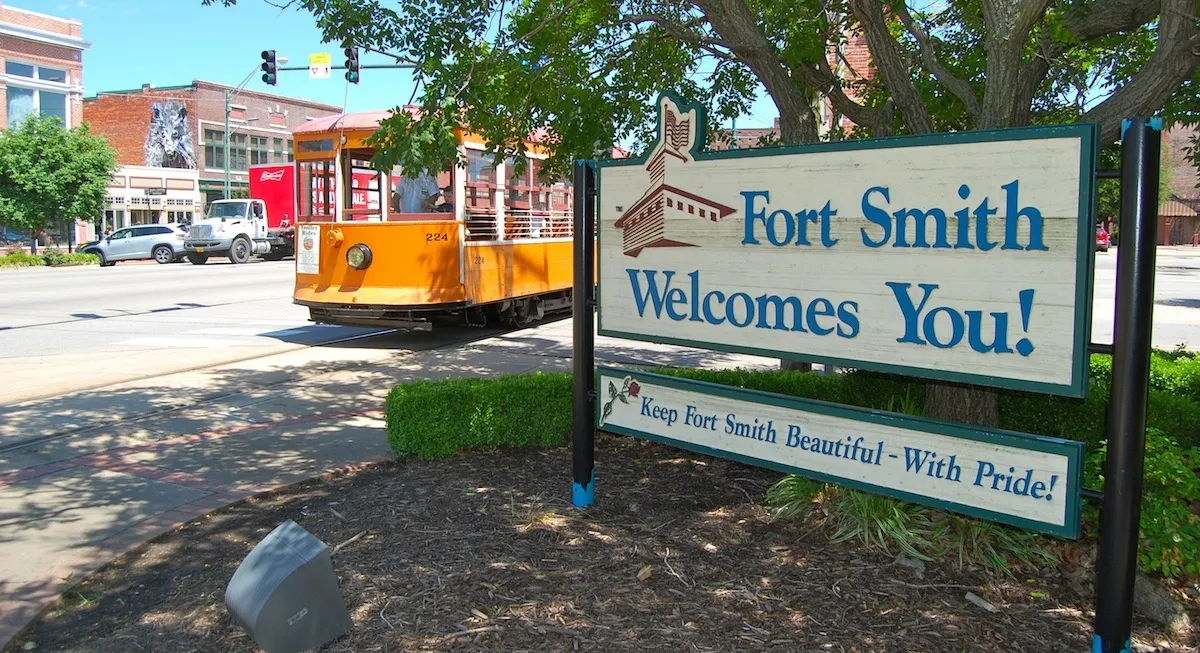 Fort Smith Arkansas welcome sign with downtown street and trolley in the background