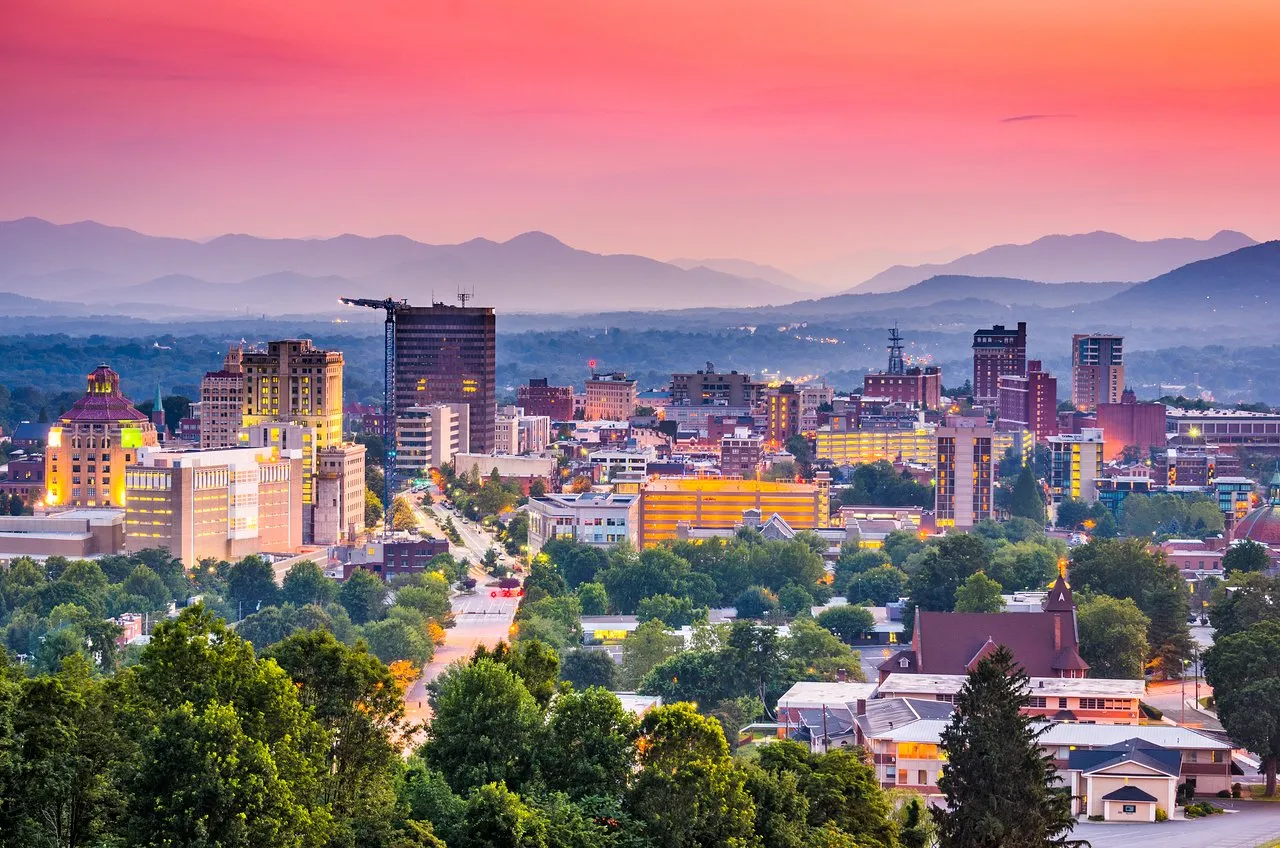 Asheville North Carolina skyline at sunset with downtown buildings and Blue Ridge Mountains in the background