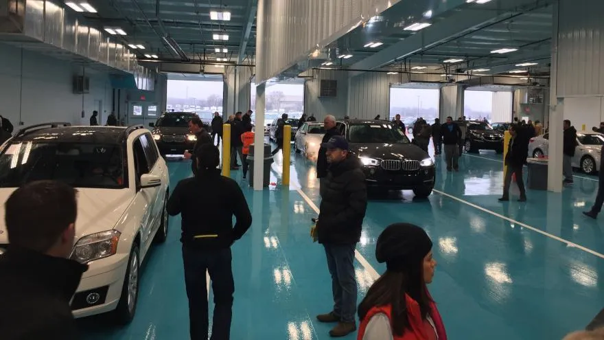 Indoor auto auction with buyers inspecting vehicles during a live car sale event at a wholesale auction facility