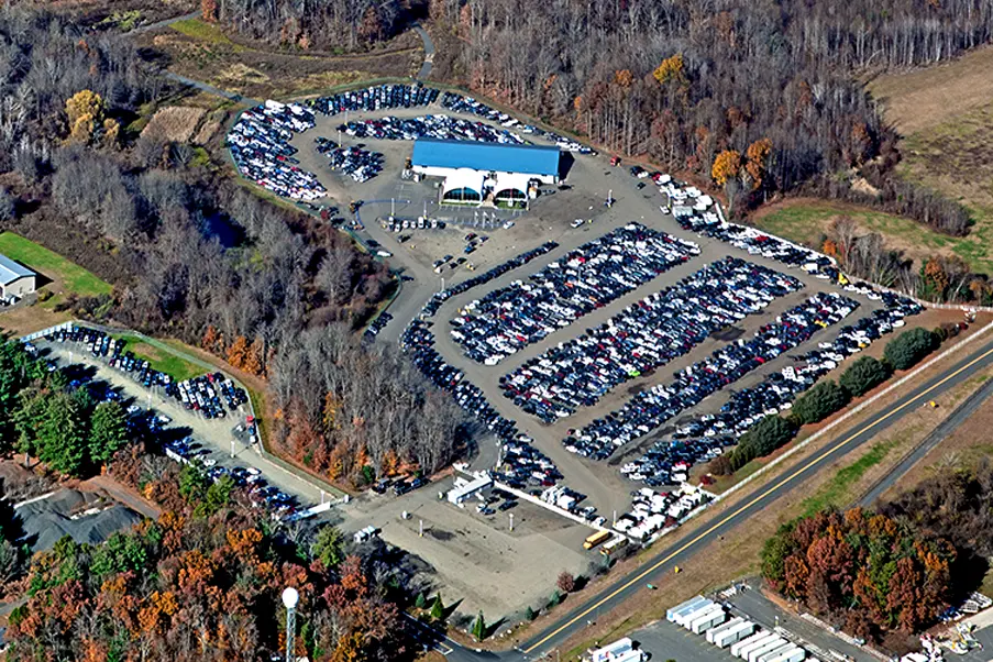 Aerial view of a large car auction facility with rows of vehicles parked for wholesale auto sales and transport pickup