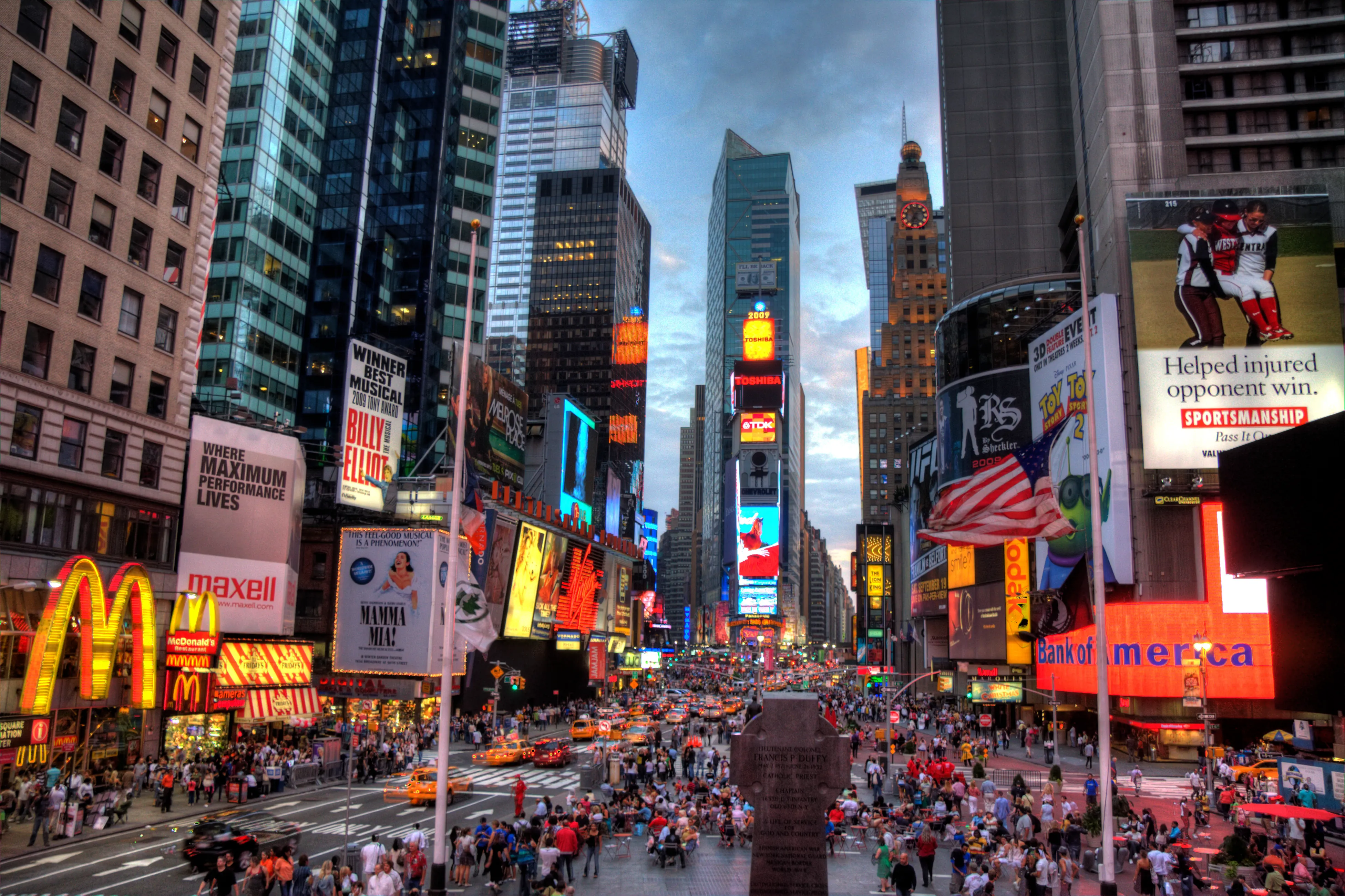 times square in new york city with illuminated billboards, traffic, and crowds at night