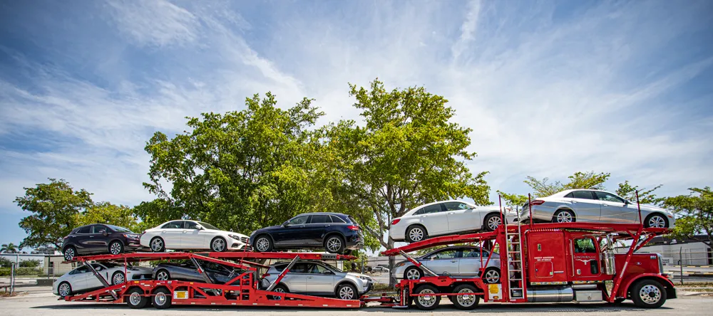 Vehicle transport trailer carrying multiple cars on an open auto carrier for long distance car shipping services