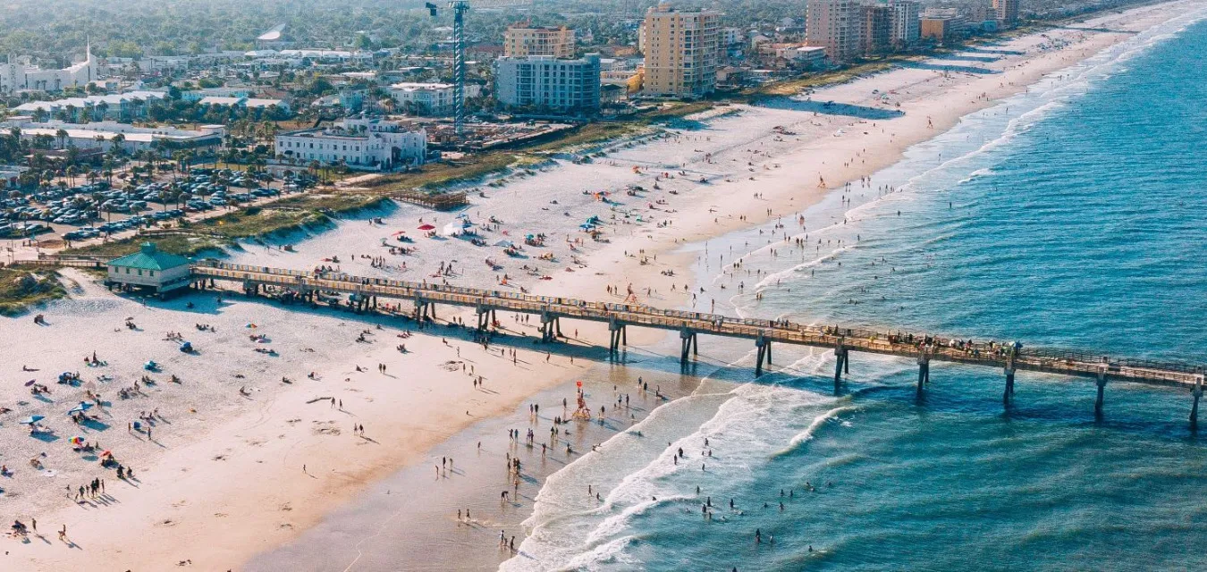 aerial view of daytona beach florida with ocean pier, sandy shoreline, and beachgoers along the coast
