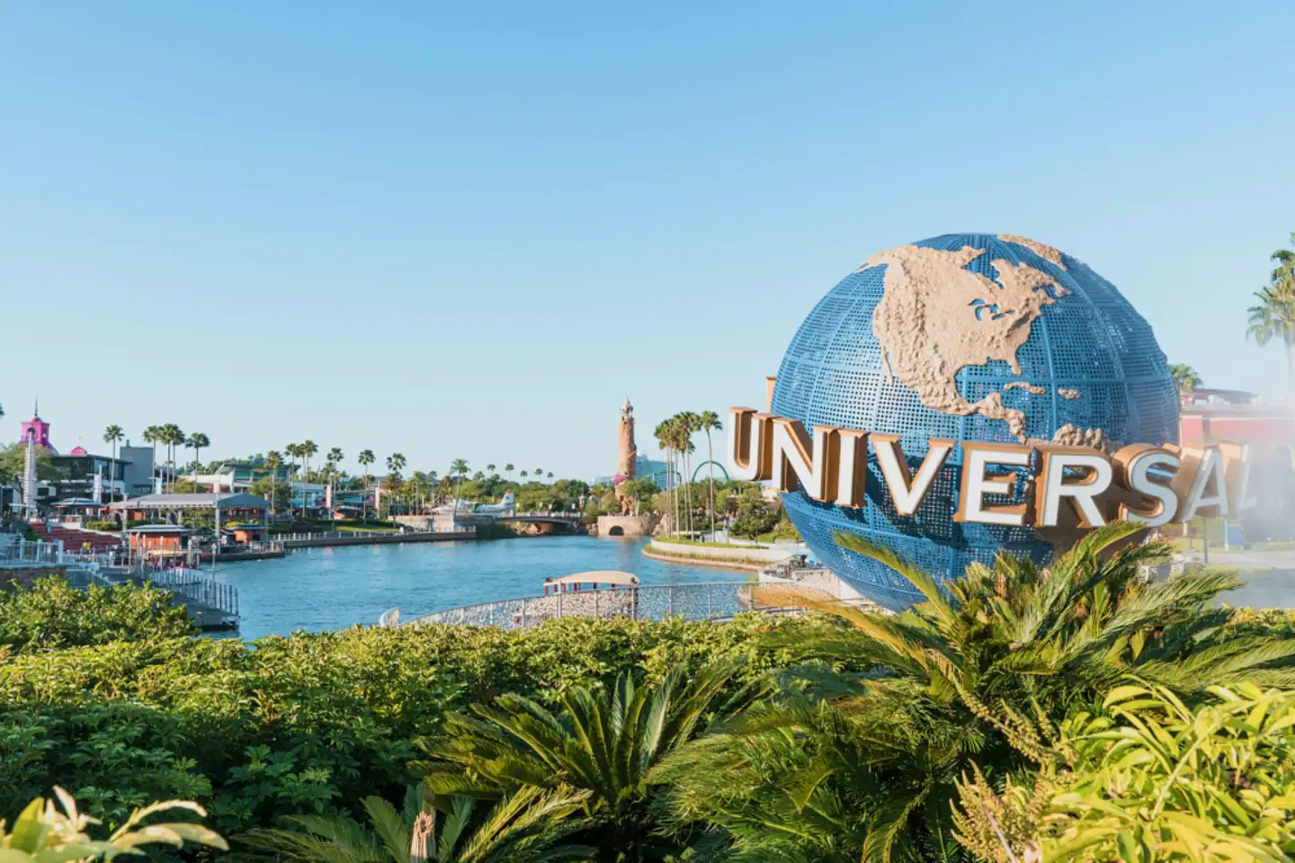 universal studios orlando globe entrance with waterway, palm trees, and theme park buildings