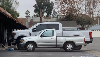small pickup parked next to lifted heavy duty truck in a parking lot showing different truck sizes
